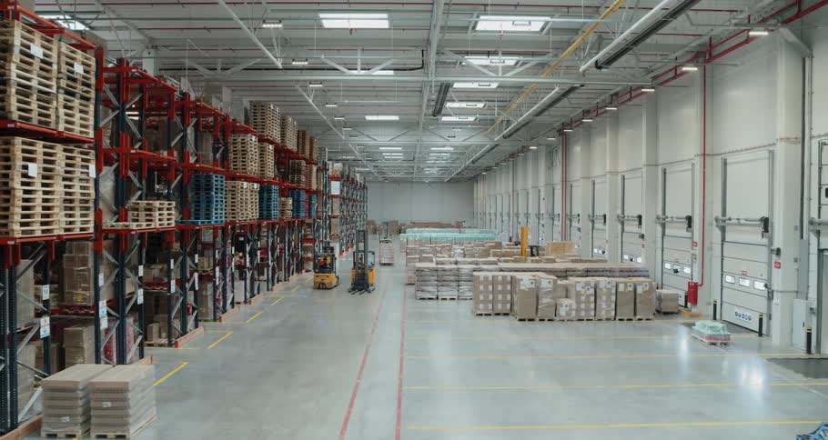 Four people drive yellow forklifts in a warehouse