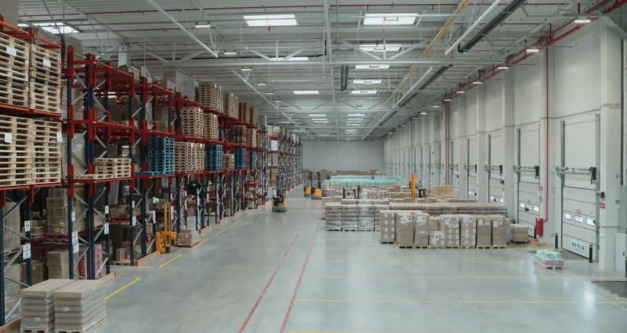 Several forklift drivers working in clean warehouse moving neatly organized products on pallets