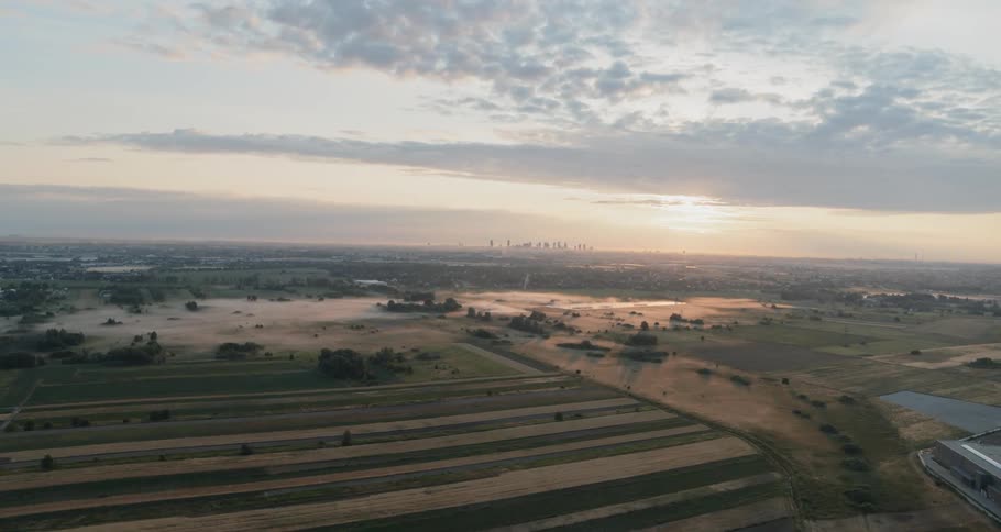 On a cloudy day a patches of fog linger over sprawling farmlands