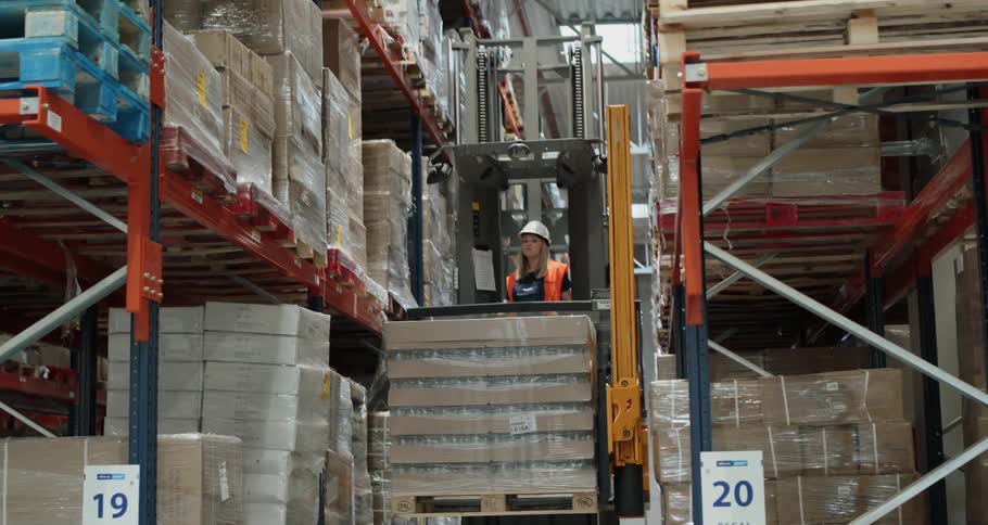 Man drives loading machine to stack merchandise in a warehouse
