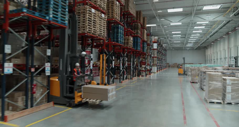 A warehouse full of supplies and people driving forklifts