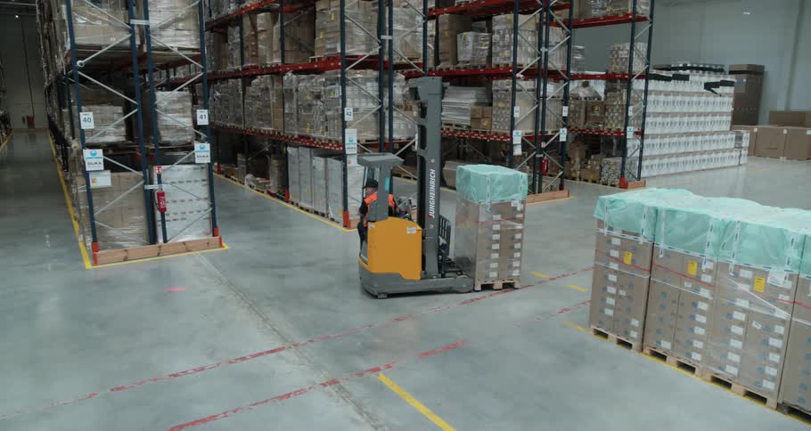 A driver uses a forklift to move pallets of items in a warehouse