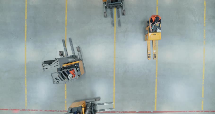 Four forklifts are driving in circles on a warehouse floor