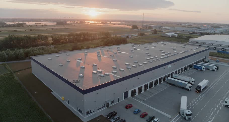 A warehouse has a few tractor trailers backed up to loading doors