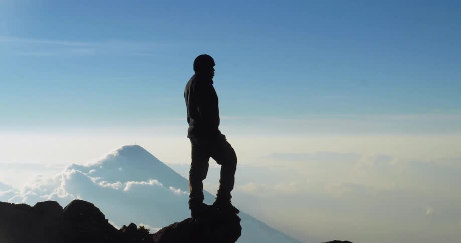 A silhouette of a man standing on top of a rock