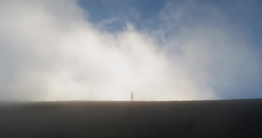 Man walks through the thick fog on the hill