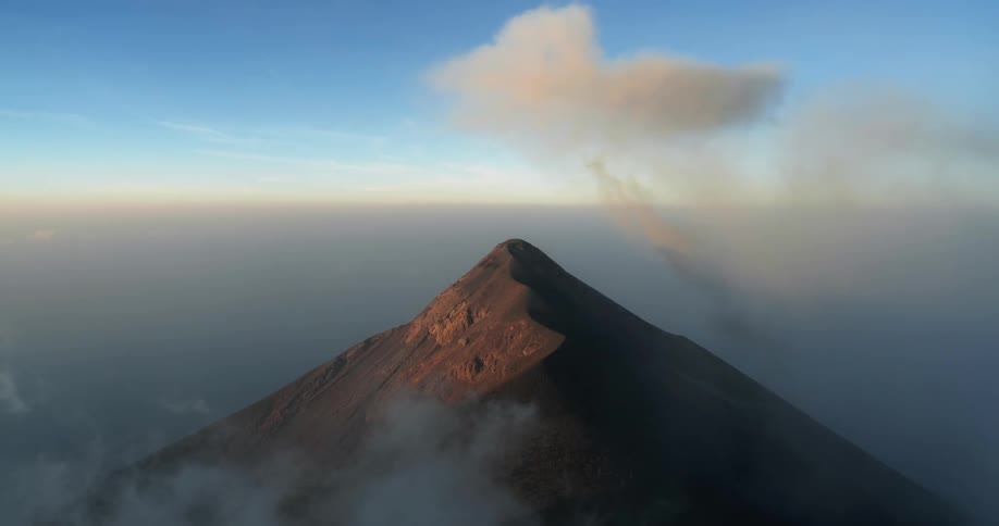 Clouds obscure all but the peak of a mountain with a clear blue sky above