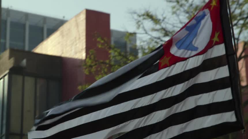 A flag is waving in front of some large buildings
