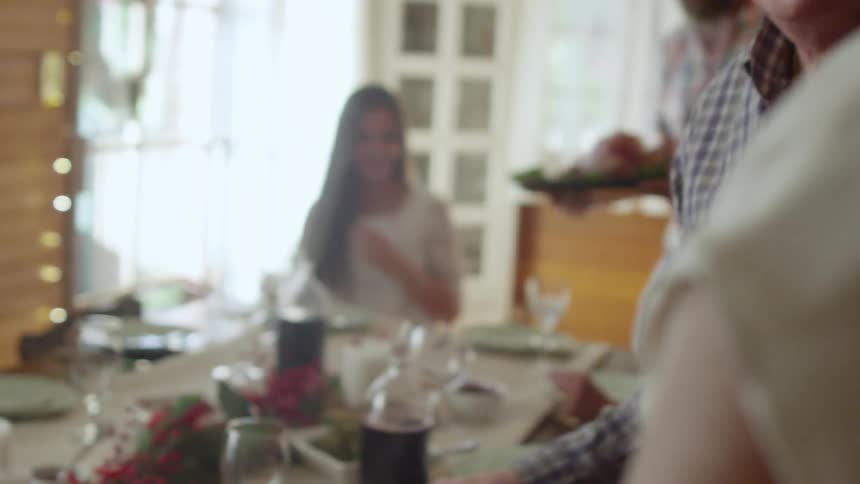 People gathering to eat a dinner at a table decorated for the holidays