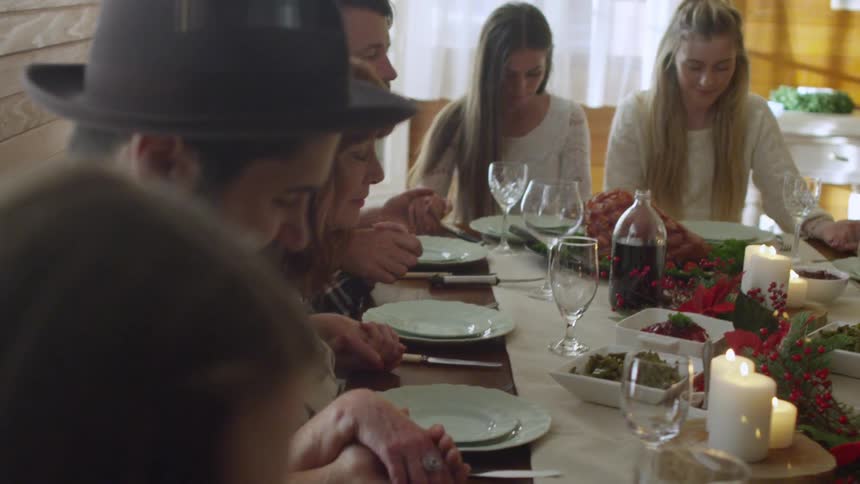 A family gathered around a table praying