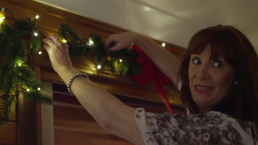 Woman hanging garland and lights above a doorway