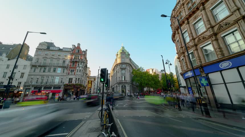 A time lapse of a busy intersection in an urban area shows a large volume of pedestrians and vehicles passing through