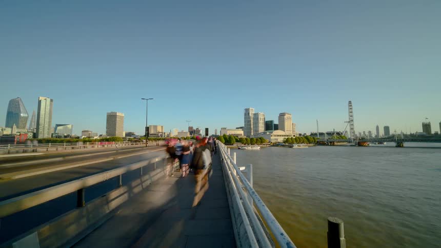 People are walking and driving over the bridge near the city
