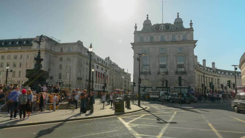 A large number of people are gathered around a fountain located next to a busy street