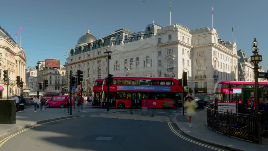 Red double decker buses stopping and going at a busy intersection in a city