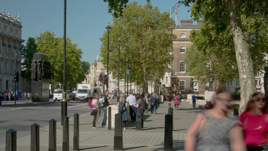 Pedestrians and traffic move in the city near buildings and trees