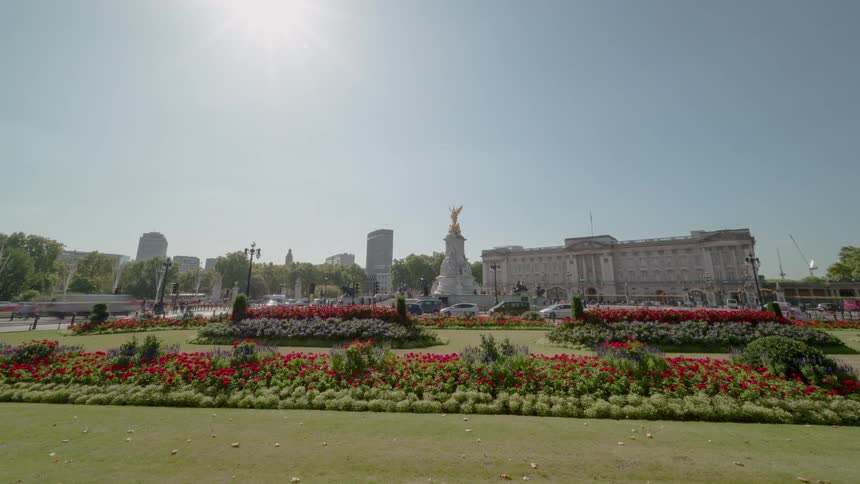 Vehicles drive down a busy road surrounding a park and government building