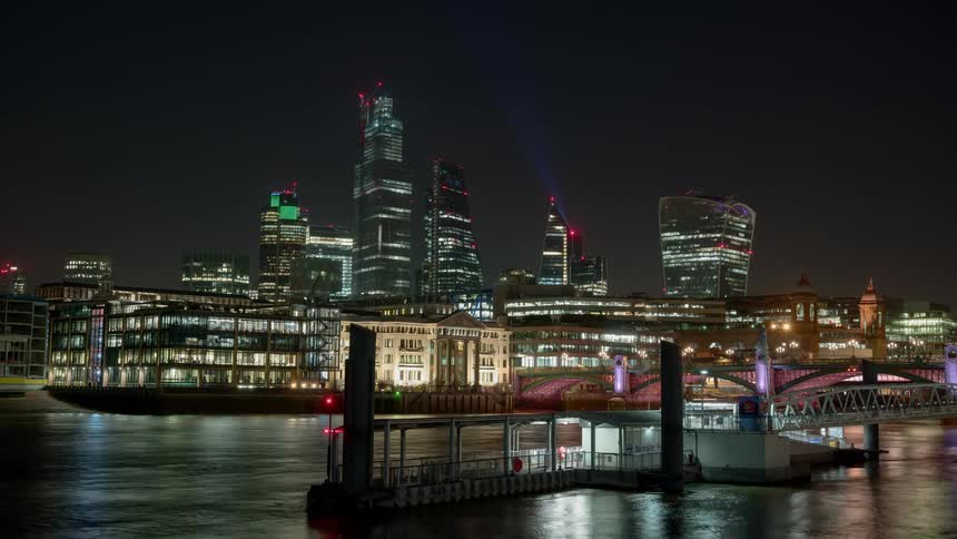 Skyline of the illuminated city with tall buildings and ferries berthing port at night