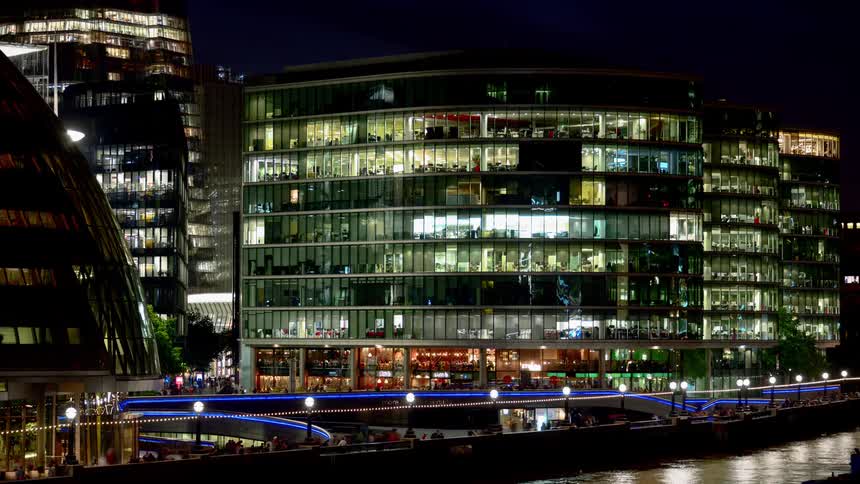 People walk in a city at night with blue lights highlighting pedestrian walkways