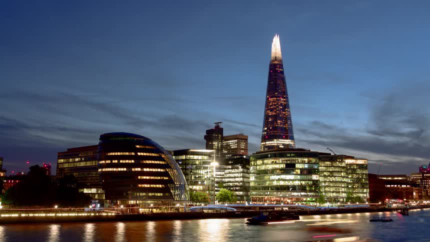 View of illuminated tall buildings next to the sea time lapse at dusk