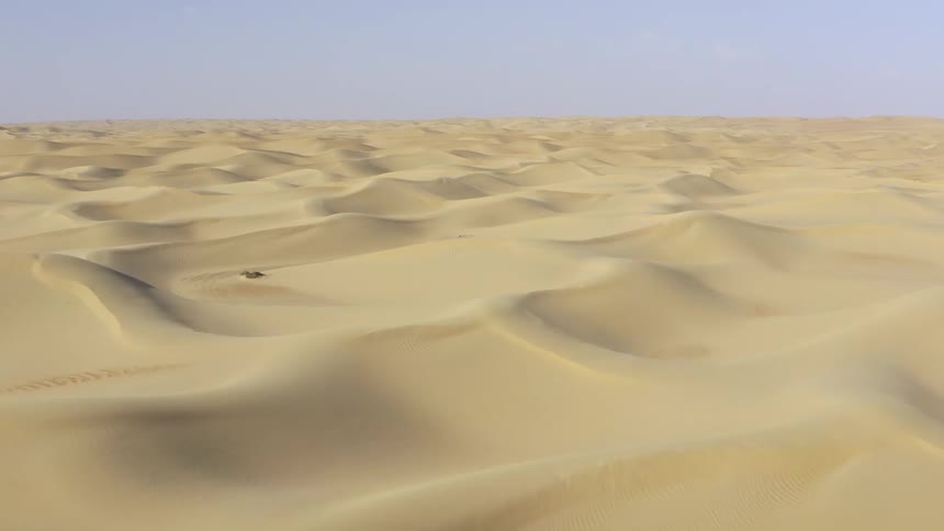 Aerial view of vast desert with sand dunes on a sunny day