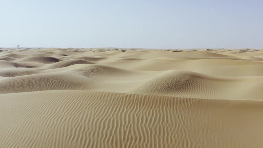 A desert with sandy dunes and the sky in the background