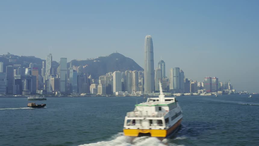 The boats sail towards the city on a foggy day