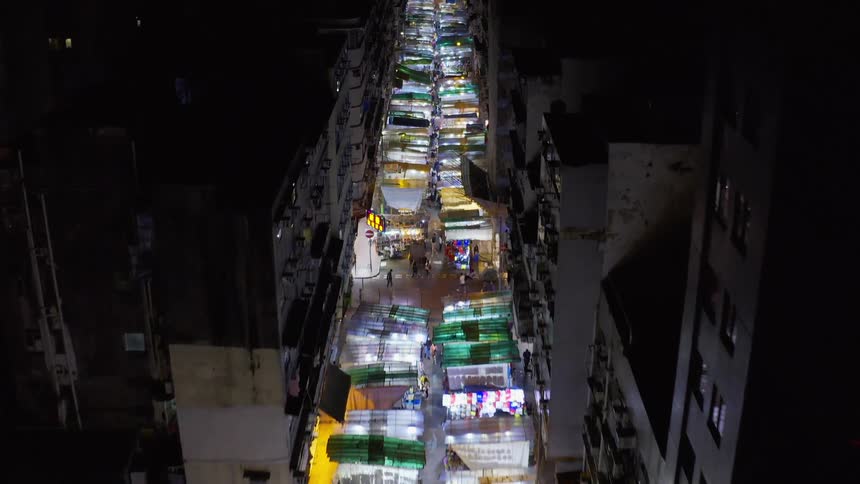 Several people are walking through a market area at night
