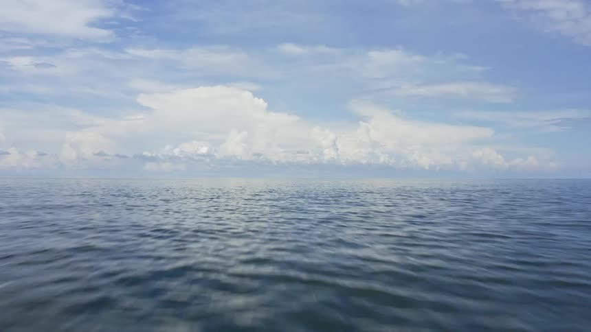 View of vast ocean with blue sky and clouds