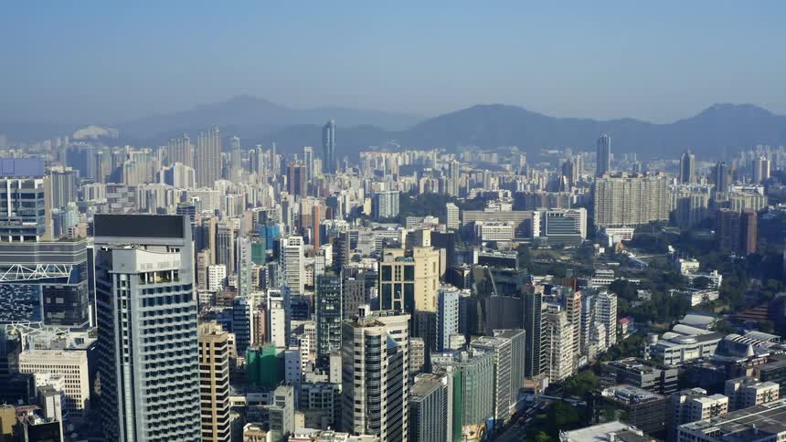 Tall buildings fill the landscape in front of a mountain range