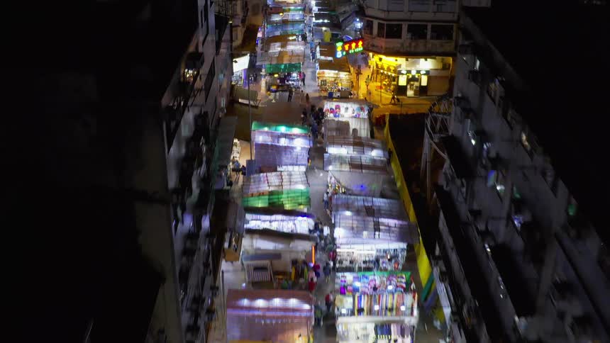 Booths along a crowded city street are shown at night
