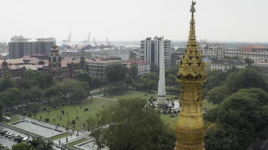 Within an urban area an ornate and elaborate tower stands near a grass covered field