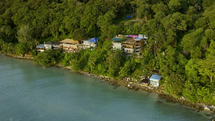 An aerial footage of buildings in the forest near a river
