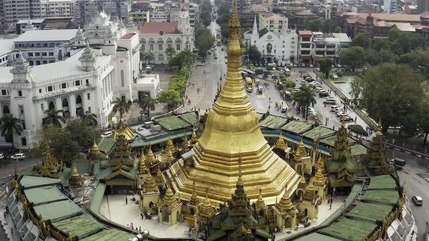 A building with a large golden spire stands in the middle of an urban area