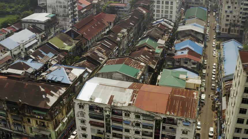 The streets of a rundown urban area are lined with vehicles