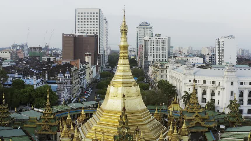 An aerial footage of a golden temple in the middle of city