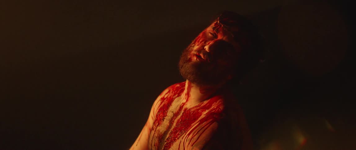 Male in pain with blooddripping from face and body against a black backdrop