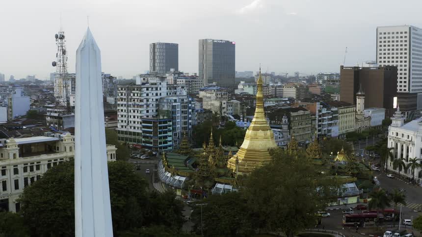 In the middle of a dense downtown area a building with a large golden steeple stands out amidst the other buildings