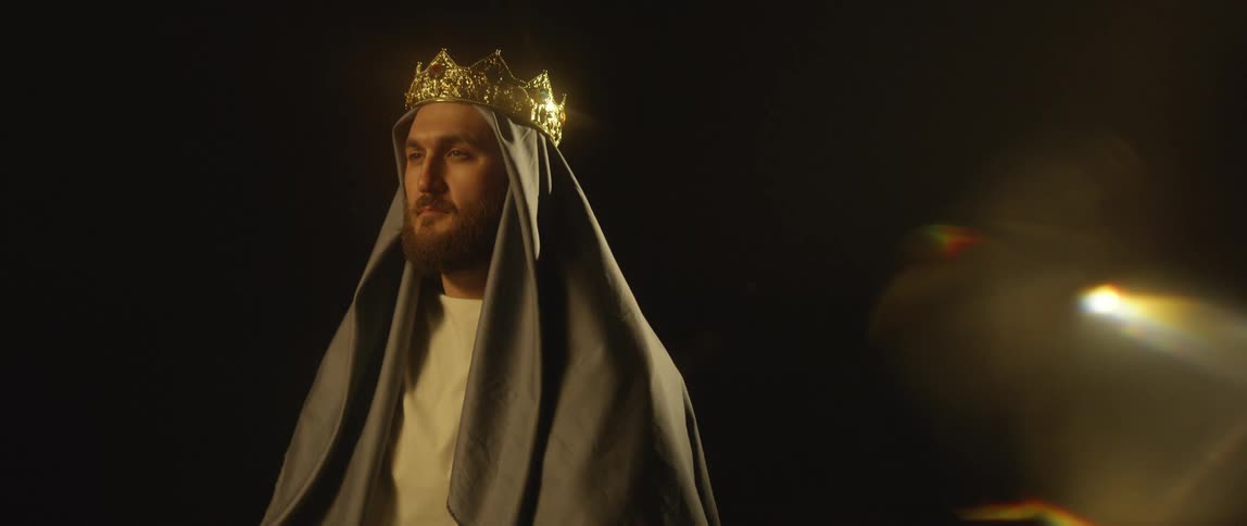 Man wearing head cloth and gold crown in dark