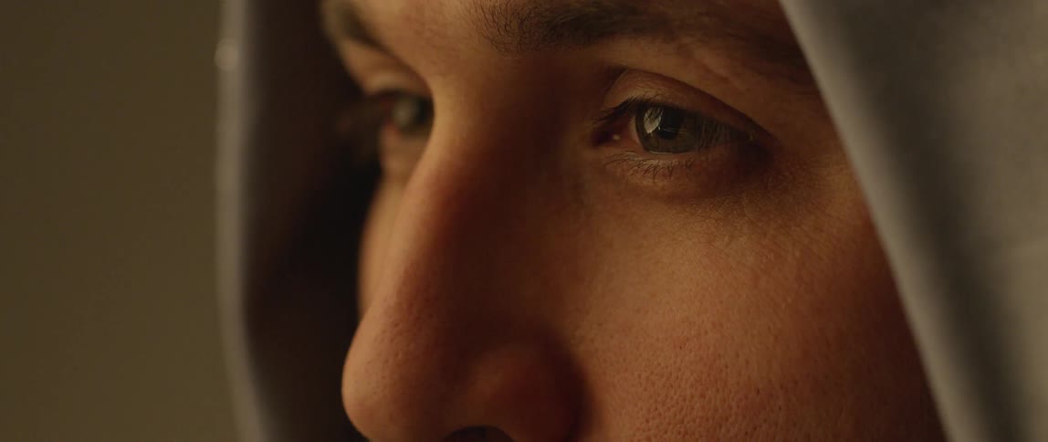 A man in a gray hood blinking his eyes