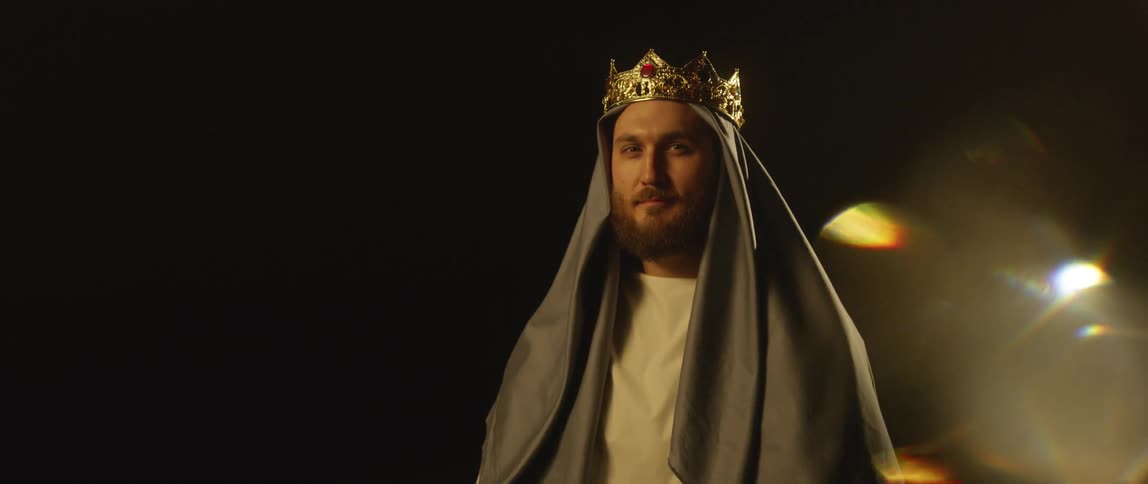 A man is dressed as jesus with a crown and cloth draped over his head