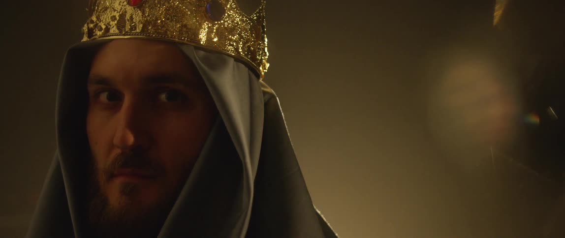 Man in head covering and crown raises head