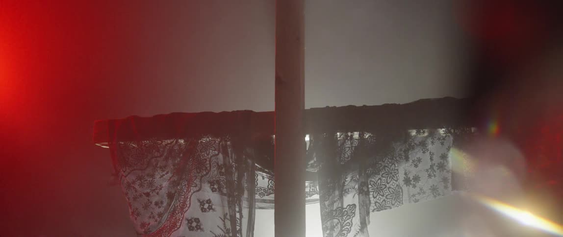 Sheer patterned fabric is draped on a large wooden cross