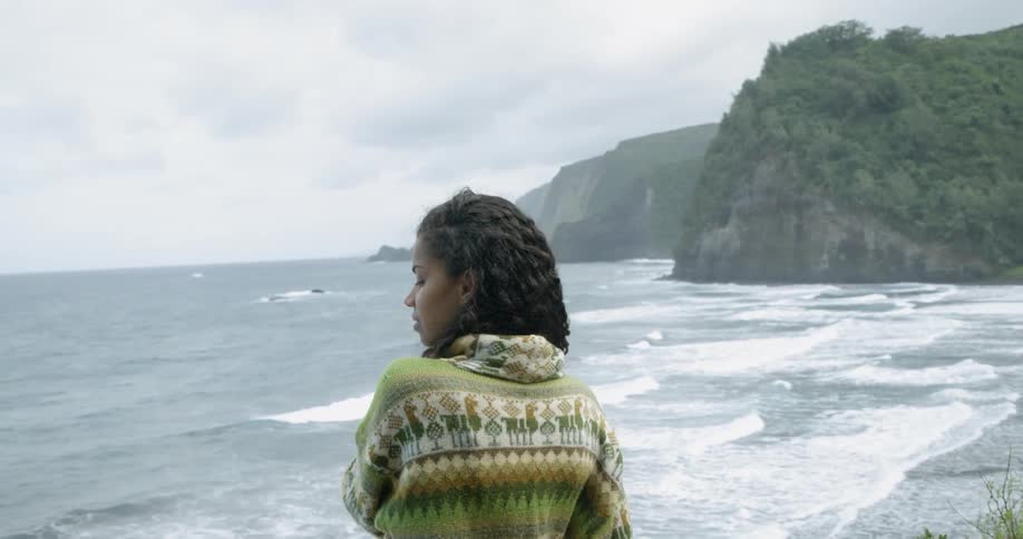 A young black woman looking out over a beach in a bay