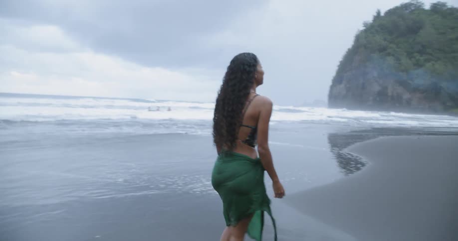 A woman is walking along a beach and turns around multiple times