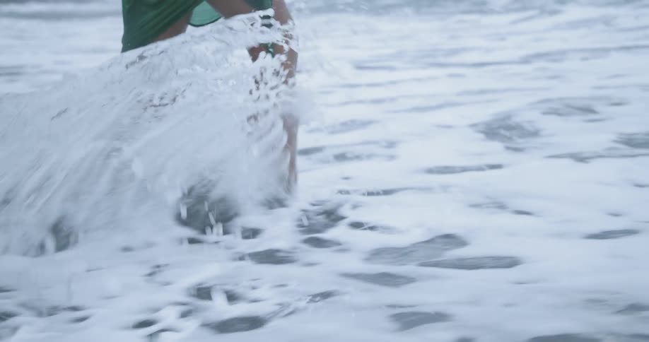 A woman walking into the tide on a beach
