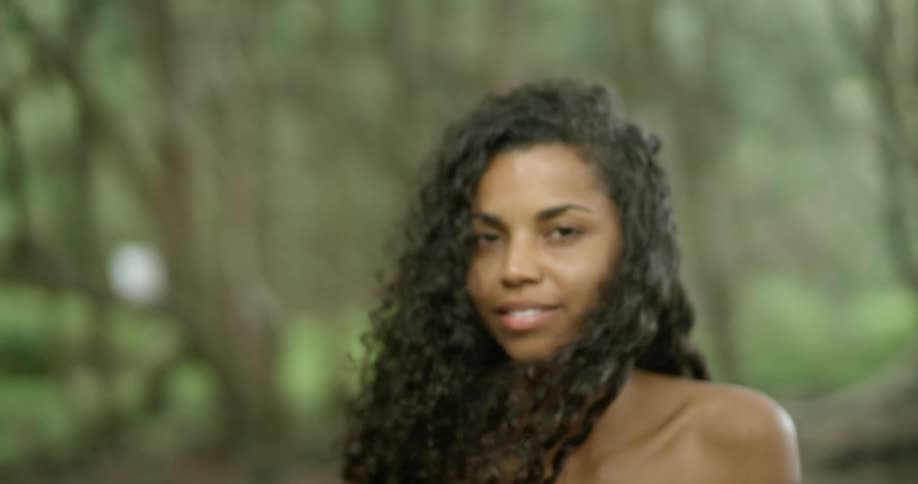 A womans dark curly hair is blowing in the breeze