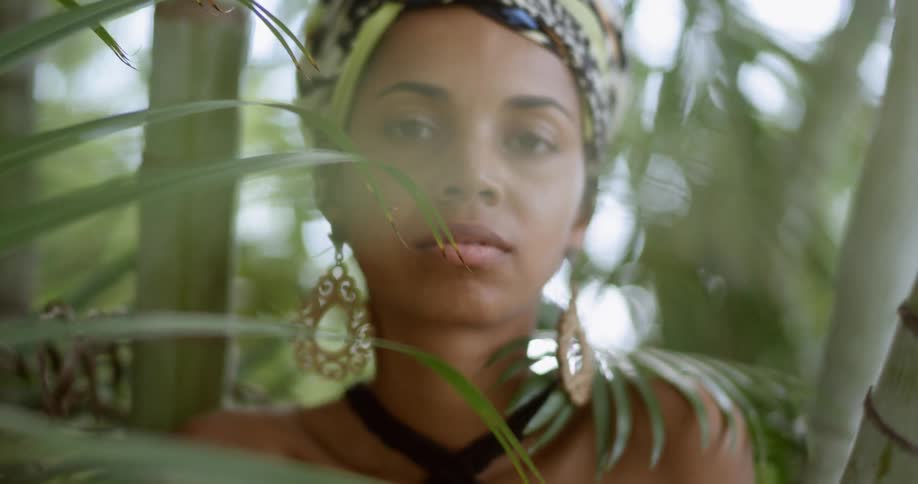 A woman standing and staring surrounded by plants