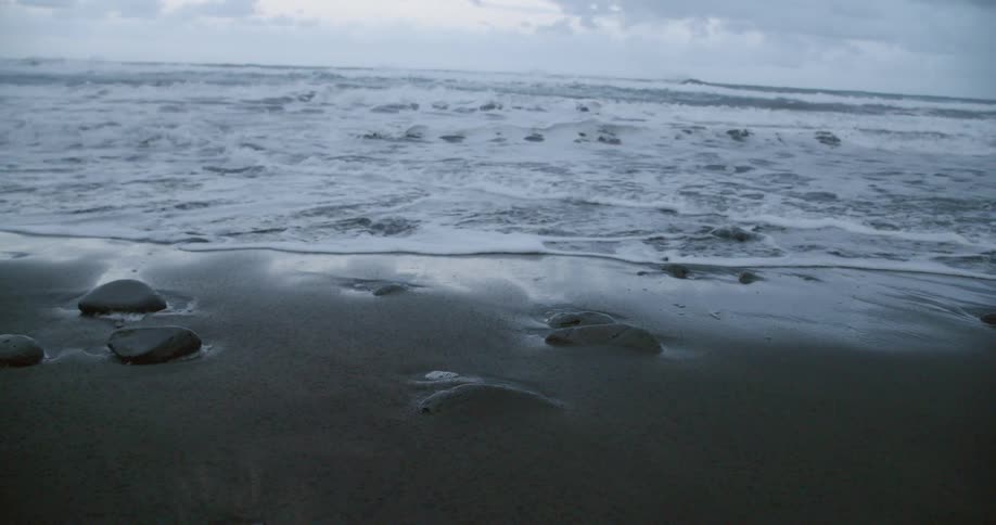 The rough waves roll into shore under a cloudy sky