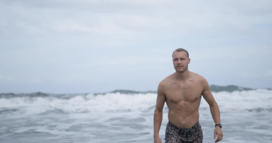 A man walking on the beach with the water and the sky in the background